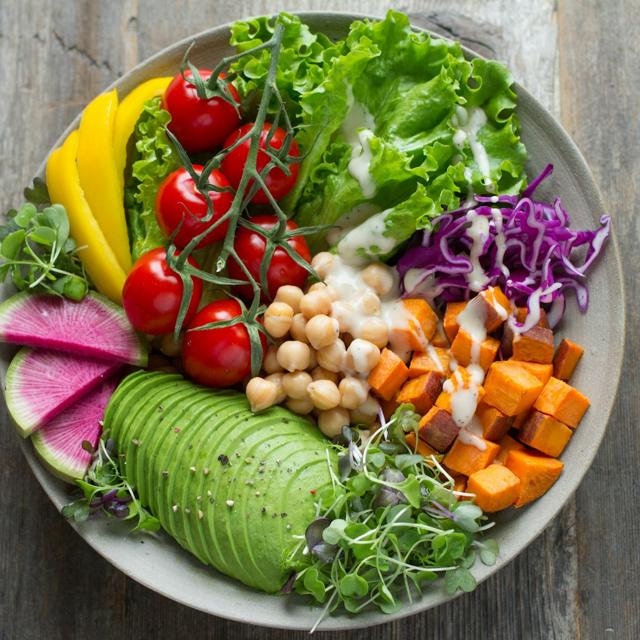 Plato con muchos vegetales: tomates, palta, garbanzos, zanahoria y hojas verdes